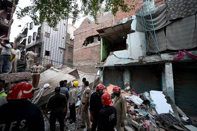NEW DELHI, INDIA - OCTOBER 7: National Disaster Response Force (NDRF) jawans, Delhi Fire Service personnel, and local residents navigate heavy rubble during a search and rescue operation after a four-storey residential building collapsed in the New Seemapuri area of Shahdara on October 7, 2026, in New Delhi, India. The structural collapse occurred around 3:30 PM behind the local fish market, trapping multiple residents under concrete slabs and damaging two adjoining houses. At least one minor died while eight people were rescued and rushed to Rajiv Gandhi Super Speciality Hospital for emergency medical treatment as sniffer dogs and excavators worked late into the evening to locate remaining trapped survivors. (Photo by Ishant Chauhan Hindus