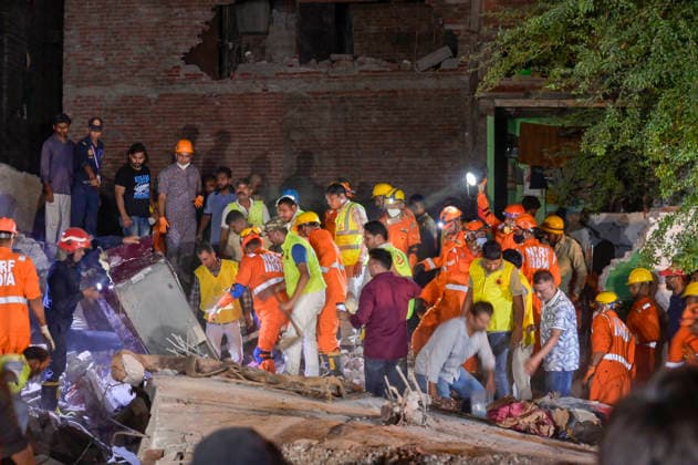 NEW DELHI, INDIA - OCTOBER 7: National Disaster Response Force (NDRF) jawans, Delhi Fire Service personnel, and local residents navigate heavy rubble during a search and rescue operation after a four-storey residential building collapsed in the New Seemapuri area of Shahdara on October 7, 2026, in New Delhi, India. The structural collapse occurred around 3:30 PM behind the local fish market, trapping multiple residents under concrete slabs and damaging two adjoining houses. At least one minor died while eight people were rescued and rushed to Rajiv Gandhi Super Speciality Hospital for emergency medical treatment as sniffer dogs and excavators worked late into the evening to locate remaining trapped survivors. (Photo by Raj K Raj Hindustan T