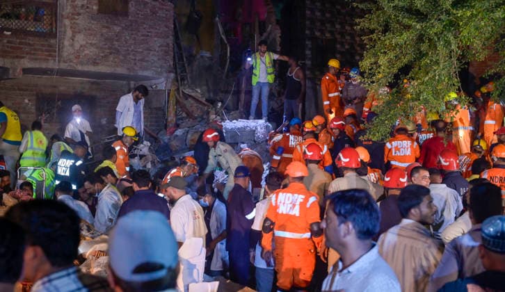 NEW DELHI, INDIA - OCTOBER 7: National Disaster Response Force (NDRF) jawans, Delhi Fire Service personnel, and local residents navigate heavy rubble during a search and rescue operation after a four-storey residential building collapsed in the New Seemapuri area of Shahdara on October 7, 2026, in New Delhi, India. The structural collapse occurred around 3:30 PM behind the local fish market, trapping multiple residents under concrete slabs and damaging two adjoining houses. At least one minor died while eight people were rescued and rushed to Rajiv Gandhi Super Speciality Hospital for emergency medical treatment as sniffer dogs and excavators worked late into the evening to locate remaining trapped survivors. (Photo by Raj K Raj Hindustan T