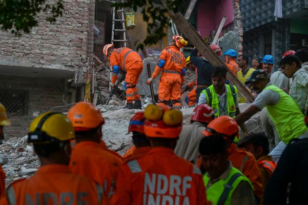 NEW DELHI, INDIA - OCTOBER 7: National Disaster Response Force (NDRF) jawans, Delhi Fire Service personnel, and local residents navigate heavy rubble during a search and rescue operation after a four-storey residential building collapsed in the New Seemapuri area of Shahdara on October 7, 2026, in New Delhi, India. The structural collapse occurred around 3:30 PM behind the local fish market, trapping multiple residents under concrete slabs and damaging two adjoining houses. At least one minor died while eight people were rescued and rushed to Rajiv Gandhi Super Speciality Hospital for emergency medical treatment as sniffer dogs and excavators worked late into the evening to locate remaining trapped survivors. (Photo by Raj K Raj Hindustan T