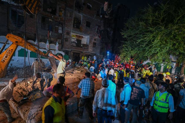 NEW DELHI, INDIA - OCTOBER 7: National Disaster Response Force (NDRF) jawans, Delhi Fire Service personnel, and local residents navigate heavy rubble during a search and rescue operation after a four-storey residential building collapsed in the New Seemapuri area of Shahdara on October 7, 2026, in New Delhi, India. The structural collapse occurred around 3:30 PM behind the local fish market, trapping multiple residents under concrete slabs and damaging two adjoining houses. At least one minor died while eight people were rescued and rushed to Rajiv Gandhi Super Speciality Hospital for emergency medical treatment as sniffer dogs and excavators worked late into the evening to locate remaining trapped survivors. (Photo by Raj K Raj Hindustan T