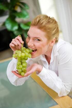 Young woman eating grapes - Model release