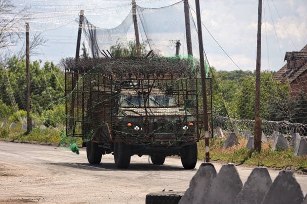 War in Ukraine: Military vehicles pass along a road lined with anti-drone nets in the Donetsk region
