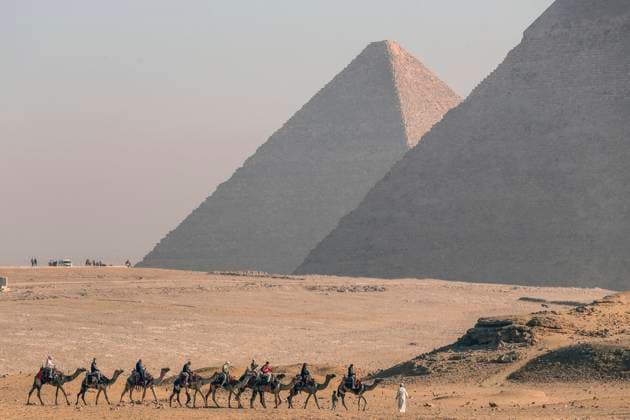 Egypt: tourists on camels in front of the Pyramids of Giza