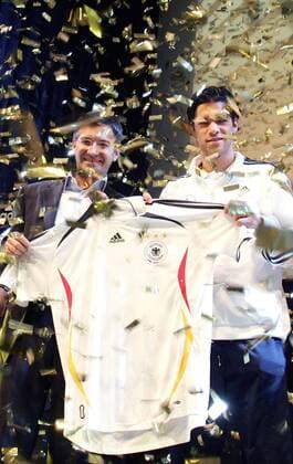 Vorstandsvorsitzender Herbert Hainer (Adidas Salomon AG, li.) und Michael Ballack (beide Deutschland) präsentieren unter goldenem Konfettiregen das neue Nationaltrikot für die Weltmeisterschaft 2006 Fußball WM Herren Nationalmannschaft 2005, Nationalteam, Nationaltrikot, Vorstellung, Präsentation, Pressetermin Gruppe Management, Unternehmensführung, Wirtschaft Köln, Vorstand, Vorsitzender, people, Industrie
