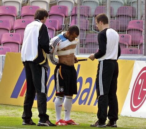 David Odonkor (Deutschland, Mitte) legt unter Aufsicht der Betreuer einen Pulsmesser an Fußball WM Herren Nationalmannschaft 2006, Nationalteam, Training, Trainingslager, Vorbereitung Gruppe Datenmessung, Pulsfrequenz, Puls, Meßgerät Genf, Leistungsüberprüfung, Pulsband