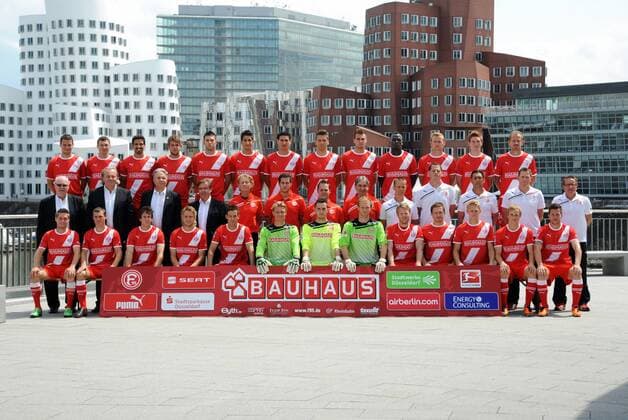 Fussball, Fototermin zur Bundesliga-Saison 2011 2012: Fortuna Düsseldorf; Mannschaftsfoto vor den Gehry-Bauten im Düsseldorfer Medienhafen: Hintere Reihe v.li.: Thomas Bröker, Oliver Fink, Adriano Grimaldi, Marco Königs, Juanan, Tugrul Erat, Karim Aouadhi, Ranisav Jovanovic, Jeron Hazaimeh, Assian Lukimya-Mulongoti, Sascha Dum, Kai Schwertfeger, Sandor Torghelle. Mittlere Reihe v.li.: Manager Wolf Werner, Orthopäde Dr. Ulf Blecker, Kardiologe Dr. Ulrich Keil, Orthopäde Dr. Alois Teuber, Physiotherapeut Bernd Restle, Physiotherapeut Jan Speckenbach, Physiotherapeut Thomas Gucek, Betreuer Aleksandar Spengler, Fitness-Coach Dirk Schauenberg, Mental-Coach Axel Zehle, Torwart-Trainer Manfred Gloger, Co-Trainer Uwe Klein, Chef-Trainer Norbert Meier. Vordere Reihe v.li.: Andreas Lambertz, Jules Schwadorf, Robbie Kruse, Ken Ilso, Jans Langeneke, Michael Ratajczak, Markus Krauss, Robert Almer, S