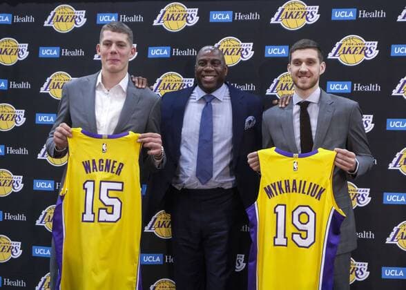 June 26, 2018 - Los Angeles, California, U.S - Los Angeles Lakers president of basketball operations, MAGIC JOHNSON, center, rookies SVIATOSLAV MYKHAILIUK, right, and MORITZ WAGNER pose with their new jerseys at an introductory press conference PK Pressekonferenz The Lakers introduce two new draft players, Wagner, originally from Germany, the 25th pick in the 2018 NBA Basketball Herren USA Draft and guard Mykhailiuk, originally from Ukraine. Lakers Introduce 2018 Draft Acquisitions - ZUMAc68_ 20180626_zaf_c68_050 Copyright: xRingoxChiux