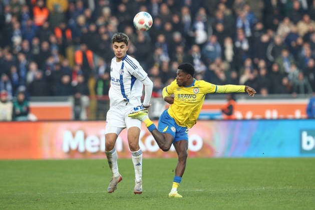 21 12 2025, xtgx, Football 2 Bundesliga, Eintracht Braunschweig FC Schalke 04 v l Mertcan Ayhan Schalke, 43 , Christian Conteh Braunschweig, 32 duel, duel, fight, tackle injured, injury, injured DFL DFB DFB REGULATIONS PROHIBIT ANY USE OF PHOTOGRAPHS as IMAGE SEQUENCES and or QUASI VIDEO Braunschweig