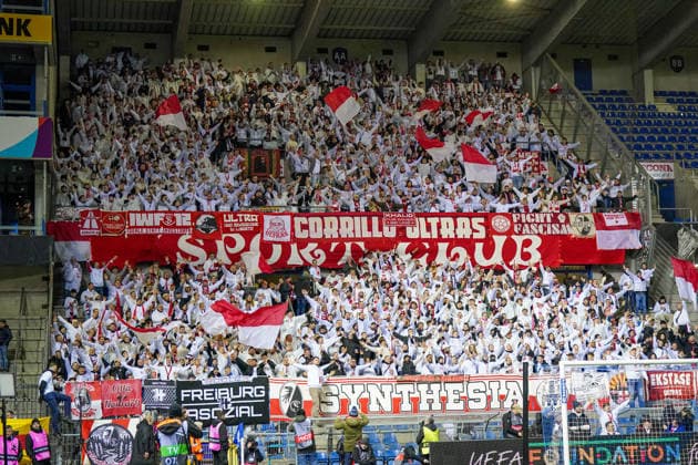 Belgium Soccer Europa League 2025 2026, Round of 16 KRC Genk vs SC Freiburg Cegeka Arena Genk Genk, Belgium, Europa fan block of SC Freiburg in the Cegeka Arena stadium during a UEFA Europa League match against KRC Genk, away fans with red and white flags, Ultras, banner Corrillo Ultras, Synthesia, Fight Fascism, Freiburg fan culture, guest stand, European Cup, international club football, stadium atmosphere, floodlit match, football fans, supporters, grandstand, matchday, UEFA Europa League Copyright: xJOERANxSTEINSIEKx