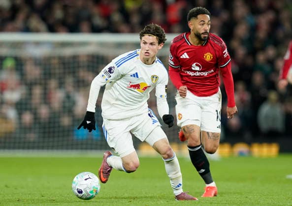 Manchester, England, 13th April 2026. Brenden Aaronson of Leeds United with the ball ahead of Matheus Cunha of Manchester United, ManU during the Manchester United vs Leeds United Premier League match at Old Trafford, Manchester. Picture credit should read: Andrew Yates Sportimage EDITORIAL USE ONLY. No use with unauthorised audio, video, data, fixture lists, club league logos or live services. Online in-match use limited to 120 images, no video emulation. No use in betting, games or single club league player publications. SPI_066_AY_Man_Utd_Leeds SPI-4684-0066