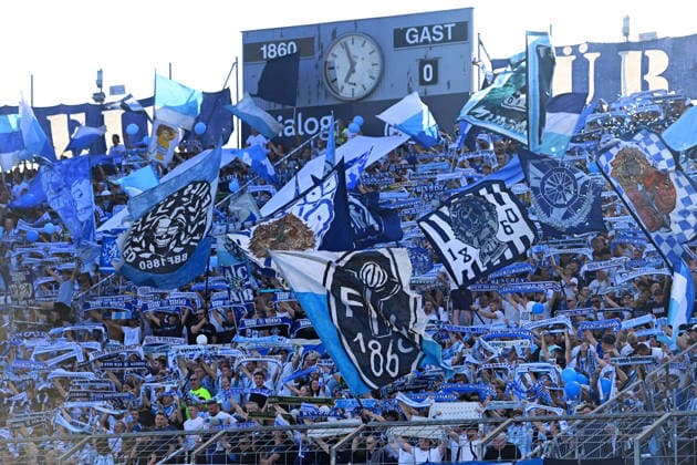 Packed 1860 fan section, fans, soccer fans with flags, new club crest, club logo,Atmosphere at the Bavarian Regional League soccer match, 2026–2027 season, Matchday 26–27, 3: TSV 1860 Munich vs. FC Augsburg II, 2–2 on August 7, 2026, at the Grünwalder Stadion in Munich