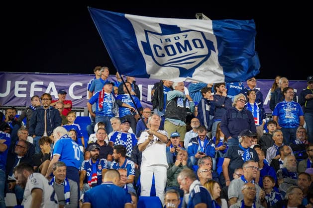 Italy Soccer UEFA Champions League 2026–2027, Matchday 1: Como 1907 vs. RB Leipzig at Giuseppe Sinigaglia Stadium. Como 1907 fans and supporters in the stands at Giuseppe Sinigaglia Stadium wave a large blue-and-white club flag featuring the Como 1907 logo. Soccer, Champions League, Como 1907, spectators, fans, stands, fan section, fan culture, banner, flag, club crest, club colors, atmosphere, home fans, Italy Copyright: xJOERANxSTEINSIEKx