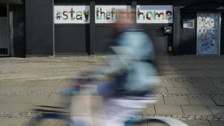 To contain the coronavirus, business closures, restrictions and contact restrictions have been ordered and curfews are being discussed, the photo shows a cyclist, cyclist in front of a banner, banner, poster, notice, writing on a building with the words, hashtag stay the fuck home, stay at home, stayathome, stay at home, stay at home, contact ban, contact ban, xobx