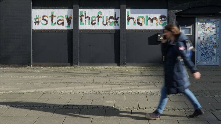 To contain the coronavirus, business closures, restrictions and contact restrictions have been ordered and curfews are being discussed, the photo shows a pedestrian in front of a banner, banner, poster, notice, writing on a building with the words, hashtag stay the fuck home, stay at home, stayathome, stay at home, stay at home, contact ban, contact ban, curfew, 25 03 2020, xobx