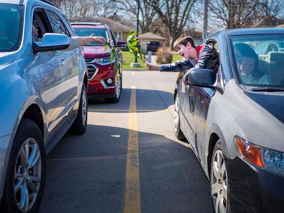 Coronavirus in den USA, Drive-Through Gottesdienst zum Auftakt der Karwoche in Des Moines, Iowa April 5, 2020, Des Moines, Iowa, U.S: LIAM MATTES, 7, reaches with his palm branch for the car parked next to his during a drive through Palm Sunday service sponsored by Luther Memorial Church on the campus of Grand View University in Des Moines. About 150 people attended the service. They remained in their cars while the ministers read a short passage from the Bible, handed out palms and blessed them. On Sunday, 05 April, Iowa reported 868 confirmed cases of the Novel Coronavirus (SARS-CoV-2) and COVID-19. There have been 22 deaths attributed to COVID-19 in Iowa. Restaurants, bars, movie theaters, places that draw crowds are closed until 30 April. The Governor has not ordered shelter in place but several Mayors, including the Mayor of Des Moines, have asked residents to stay in their homes for all but essential needs. People are bein - ZUMAk94_ 20200405_zaf_k94_009 Copyright: xJackxKurtzx