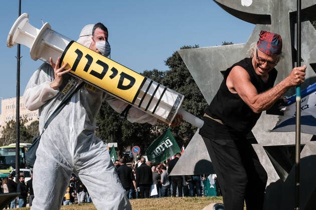 January 4, 2021, Jerusalem, Israel: A man wearing a face mask depicting Health Minister Edelstein pretends to vaccinate another with a huge syringe labeled ‘dangerâ€⠢. Demonstrators outside the parliament building protest Netanyahuâ€⠢s government, breach of trust and claims of fraud and politicization in Coronavirus management, lockdowns, violation of liberties and human rights in proposed ‘Green Passportâ€⠢ for the cured or vaccinated, nationwide financial crisis, unemployment, additional budgets for the handicapped, restaurateurs and small businesses and an assortment of other alleged ailments and demands. Jerusalem Israel - ZUMAa126 20210104_zap_a126_001 Copyright: xNirxAlonx