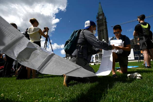 August 11, 2022, Ottawa, ON, CAN: Anh-Khoi Trinh, PhD candidate at McGill University and organizing member of the öÄuSupport Our ScienceöÄù rally, gathers up a 60 metre long petition with over 7,100 signatures, calling on the federal government to increase funding for graduate and post-doctoral scholars, on Parliament Hill in Ottawa, on Thursday, Aug. 11, 2022. Ottawa CAN - ZUMAc35_ 20220811_zaf_c35_039 Copyright: xJustinxTangx
