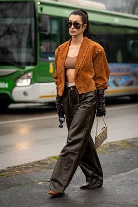 Street Style at Milan Fashion Week 2025 - Gucci in Milan, Italy on 25 February 2025 Street Style: A guest wears black Gucci sunglasses, gold earrings, silver necklace, light brown cropped suede jacket, dark brown bralette top, Gucci cream underwear, shiny black long leather gloves outside of the Gucci fashion show during the Milan Fashion Week Womenswear Fall Winter 2025 2026 in Milan, Italy on 25 February 2025., Credit:Stefano Costantino TTL Avalon Milan, Italy Copyright: xStefanoxCostantinoxTTLx xAvalonx 0968952598