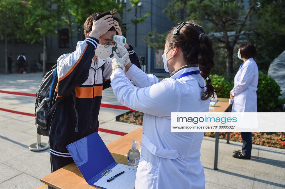 (200427) -- BEIJING, April 27, 2020 -- A staff member measures body temperature for a student at Beijing No. 161 High School in Beijing, capital of China, April 27, 2020. Senior high schools in Beijing on Monday restarted classes for seniors, who will take the national college entrance exam on July 7-10. ) CHINA-BEIJING-STUDENTS-BACK TO SCHOOL (CN) PengxZiyang