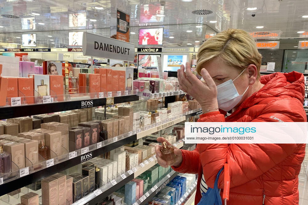 Relaxation and compulsory masks in the coronavirus pandemic Businesses in Bavaria will open again on April 27th. A woman is testing a perfume, womens fragrance, shop, branch, entrance, in a drugstore despite mouth nose protection,