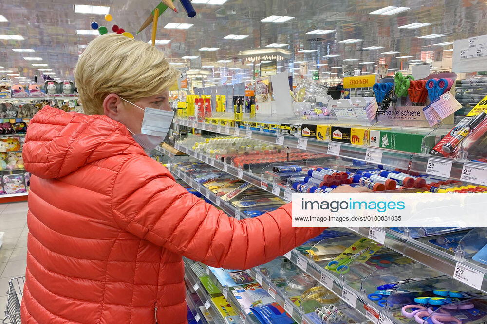 Relaxation and compulsory masks in the coronavirus pandemic Businesses in Bavaria will reopen on April 27th. A woman with a mouth nose protection in the stationery department of a drugstore store, branch, entrance,