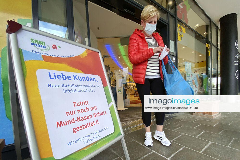 Relaxation and compulsory masks in the coronavirus pandemic Businesses in Bavaria will open again on April 27th A woman with mouth and nose protection will come from a SaniPlus pharmacy next to a notice, Operator access only allowed with mouth and nose protection ,
