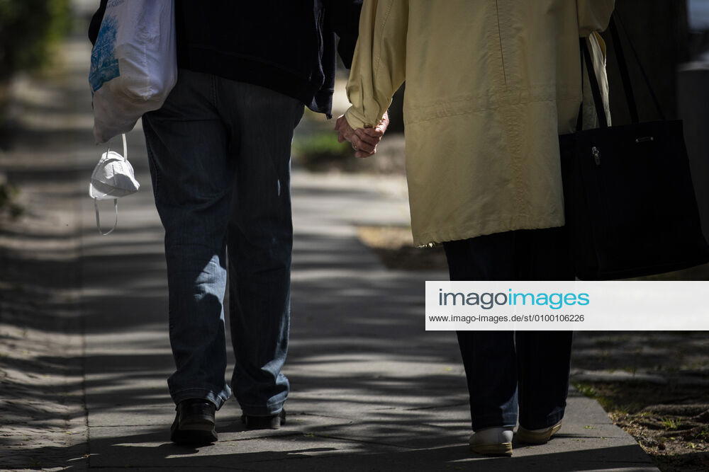 An elderly couple walking hand in hand while the man in the other hand wears a mouthguard, recorded in Berlin, 28 04 2020 There is a mask obligation in public transport throughout Germany Berlin Germany