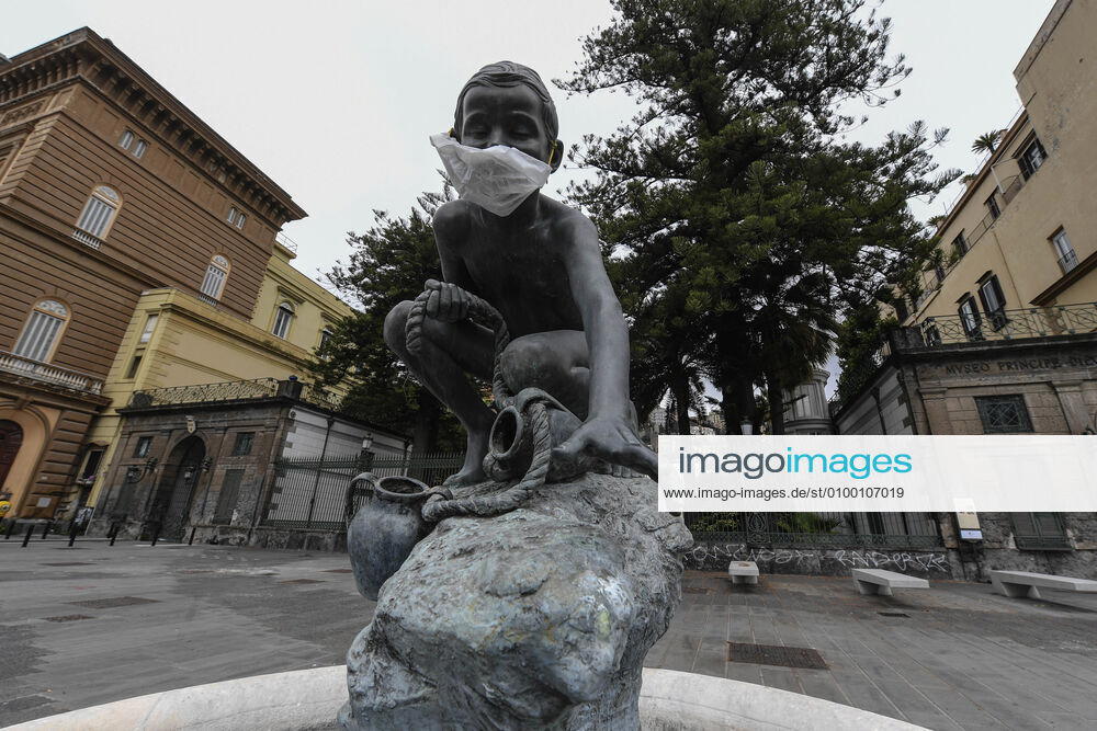 A protective mask is placed on a statue of a child fisherman, in street riviera, in Naples city. Government Decree declaring all of Italy a protected area to combat Covid-19 - Coronavirus infection.