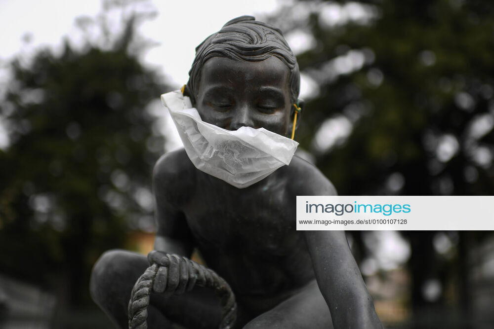 A protective mask is placed on a statue of a child fisherman, in street riviera, in Naples city. Government Decree declaring all of Italy a protected area to combat Covid-19 - Coronavirus infection.