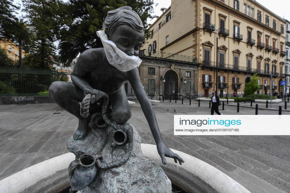 A protective mask is placed on a statue of a child fisherman, in street riviera, in Naples city. Government Decree declaring all of Italy a protected area to combat Covid-19 - Coronavirus infection.