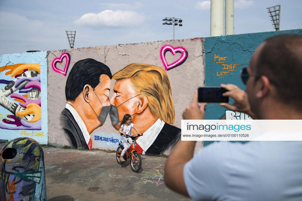 Graffiti by artist Eme Freethinker with USA President Donald Trump and Chinese President Xi Jinping kissing each other with a face mask at Mauerpark in Berlin on April 28, 2020 Since yesterday, it is mandatory to wear nose and mouth protection on trains, trams and busses Starting tomorrow, it will also be mandatory for retailers Coronavirus in Berlin