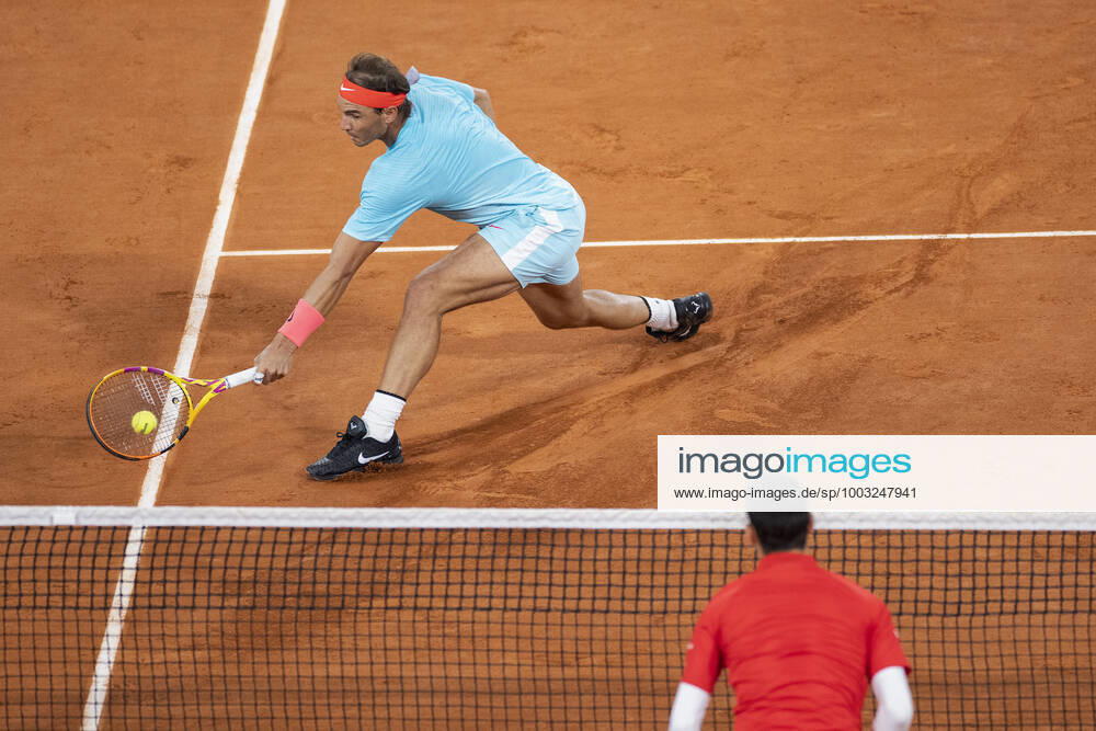 Rafael Nadal ESP plays a low backhand volley at the net, Djokovic out of focus in the foreground, from above, series, picture 1, technique