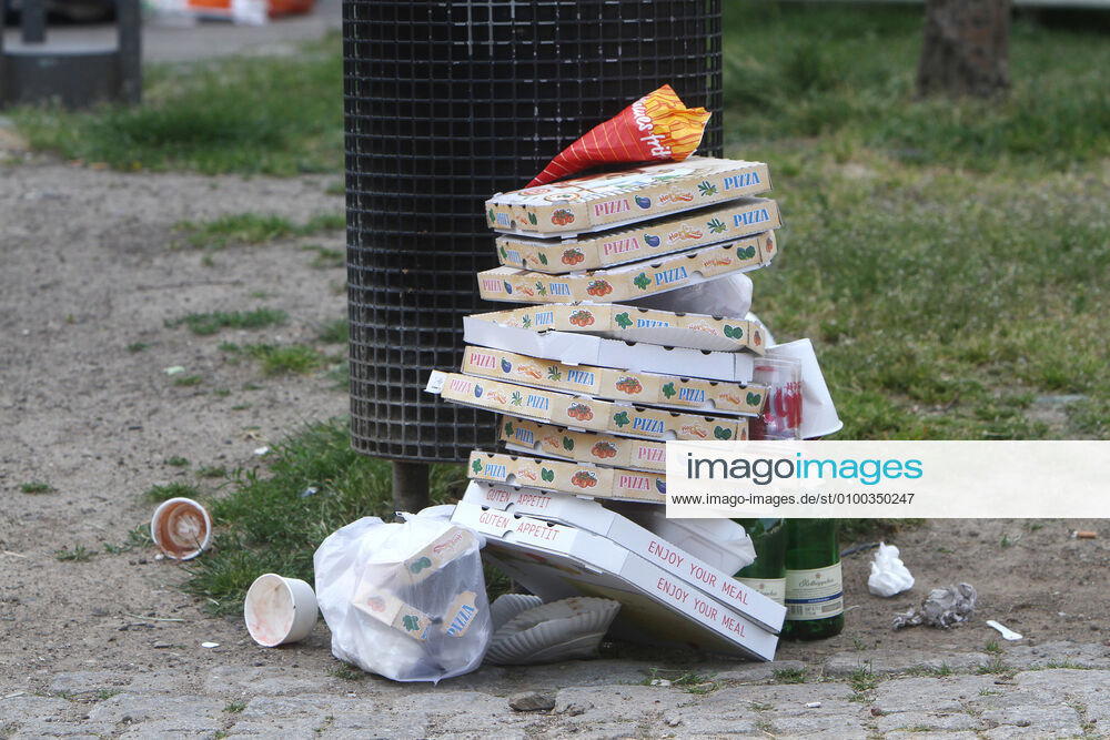 Pizza boxes pile up next to empty champagne bottles in front of an overfilled garbage can in the old town of Cologne, North Rhine-Westphalia, Germany