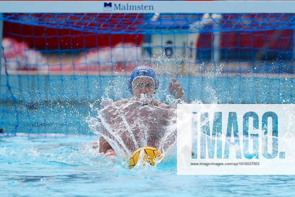 The Water polo, Wasserball match ball water splash creates a fan optical pattern illusion as it lands opposite a Romania national team, Nationalteam water polo player (back) and goalkeeper and captain Marius Tic (further aback) during the LEN European Water Polo Championships Qualifying Tournament Group C 2022 water polo match between Malta and Romania at the National Pool, Tal-Qroqq, Malta on 20 February 2022. Water Polo - Malta v Romania LEN_EQ_2022