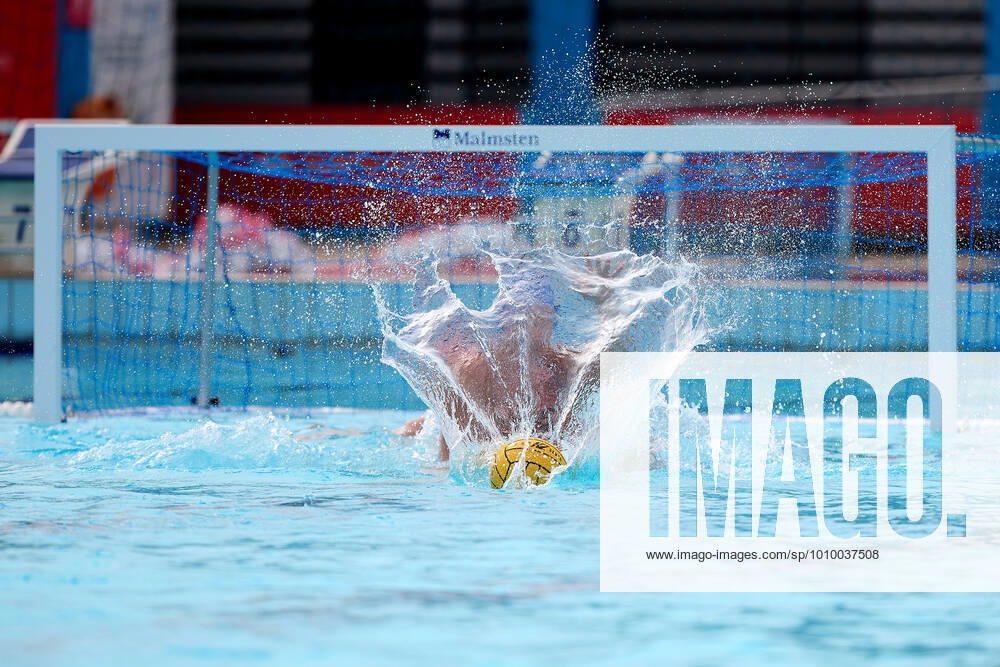 The Water polo, Wasserball match ball water splash creates a fan optical pattern illusion as it lands opposite a Romania national team, Nationalteam water polo player (back) and goalkeeper and captain Marius Tic (further aback) during the LEN European Water Polo Championships Qualifying Tournament Group C 2022 water polo match between Malta and Romania at the National Pool, Tal-Qroqq, Malta on 20 February 2022. Water Polo - Malta v Romania LEN_EQ_2022