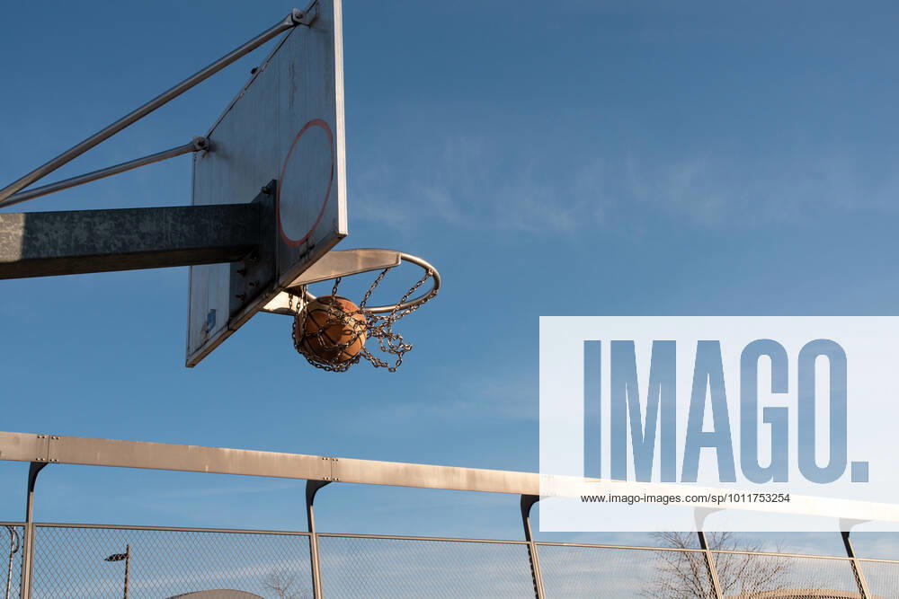 Basketball lands in the hoop. Public basketball play ground, the brown basketball flies into the basket. Frankfurt Hafenpark outdoor activities, autumn 2020.