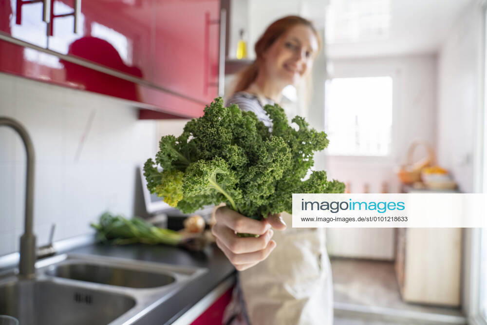 Young woman standing in kitchen, holding cale model released Symbolfoto property released AFVF06039