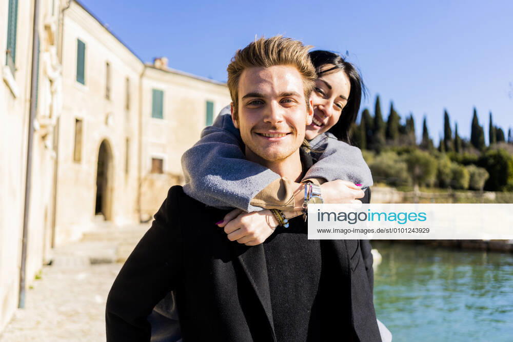 Portrait of young man carrying girlfriend piggyback at Lake Garda, Italy model released Symbolfoto GIOF08129