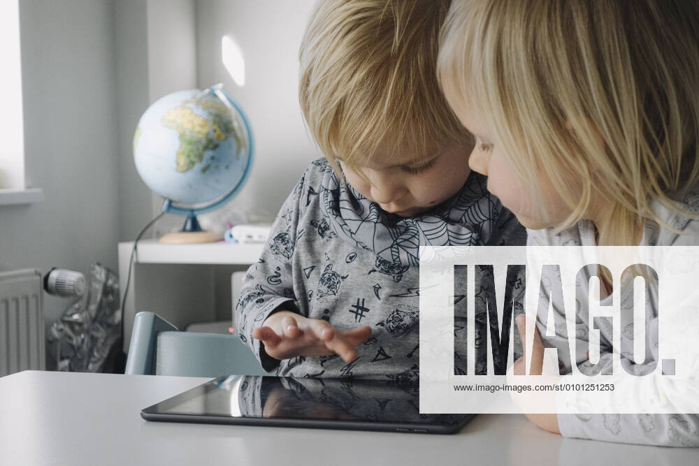 Little boy testing digital tablet while his younger sister watching him model released Symbolfoto property released JOSEF00314