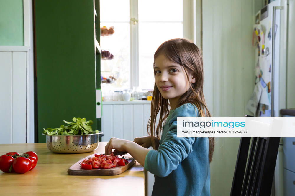 Smiling girl cutting tomatoes on chopping board in kitchen model released Symbolfoto property released LVF08809