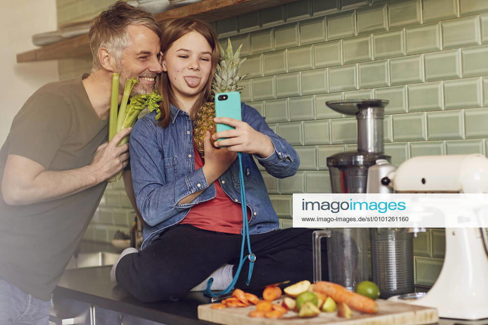 Happy father and daughter in kitchen making a selfie with fruit and vegetable model released Symbolfoto property released MCF00718