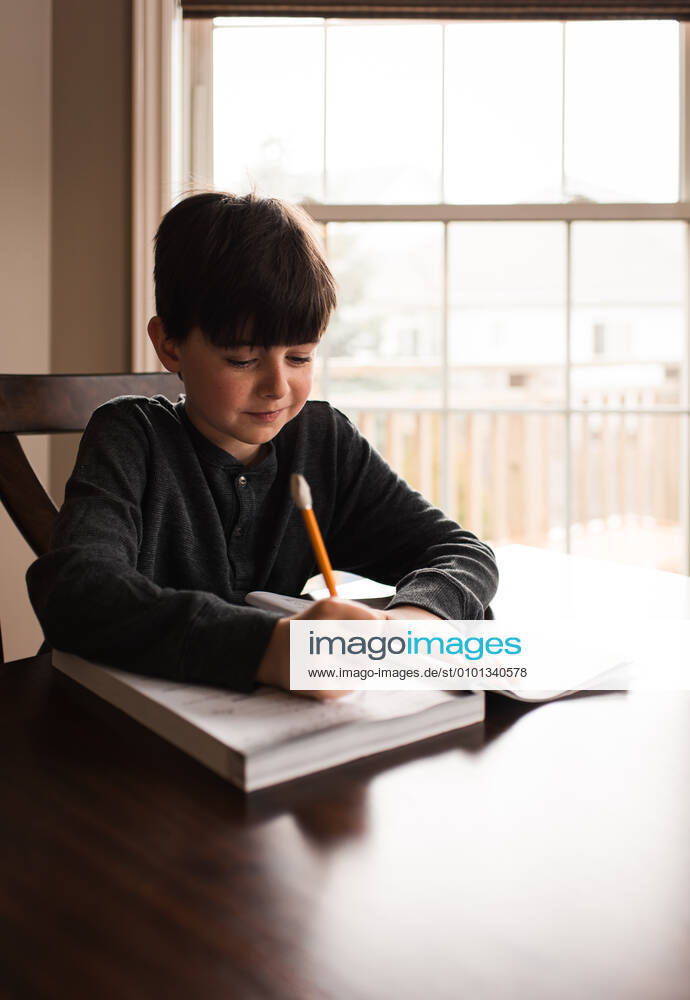 Young boy doing schoolwork in a workbook at home at the table. Kingston, ON, Canada CR_DOHO200402D-347478-01,model released, Symbolfoto