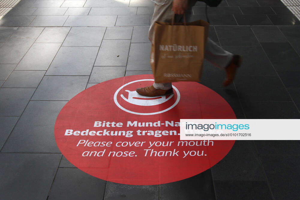 Please wear a sticker with pictogram and inscription Mouth Nose Cover on the floor of the cross platform in Frankfurt main station, Hesse, Germany