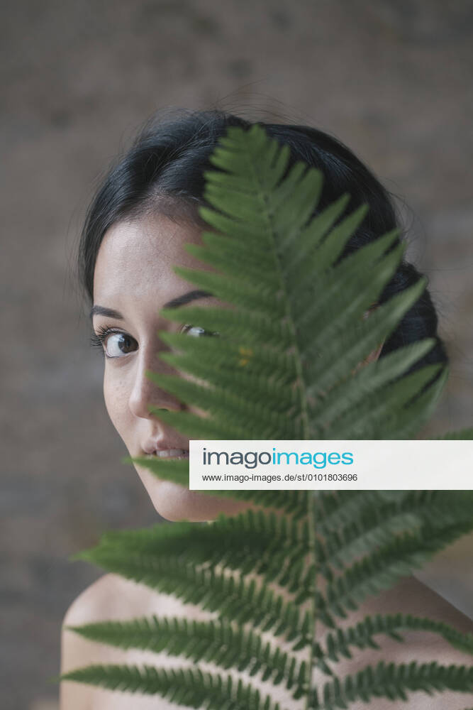 Beautiful young woman hiding behind fern leaves model released Symbolfoto ALBF01237
