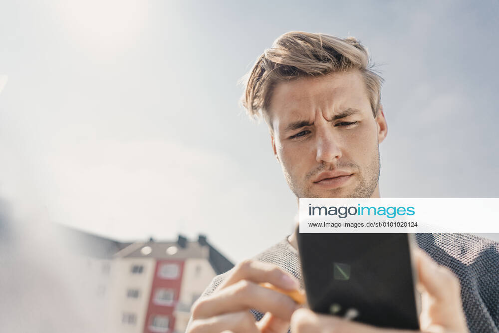 Young man using smartphone on the bacony model released Symbolfoto property released KNSF08053