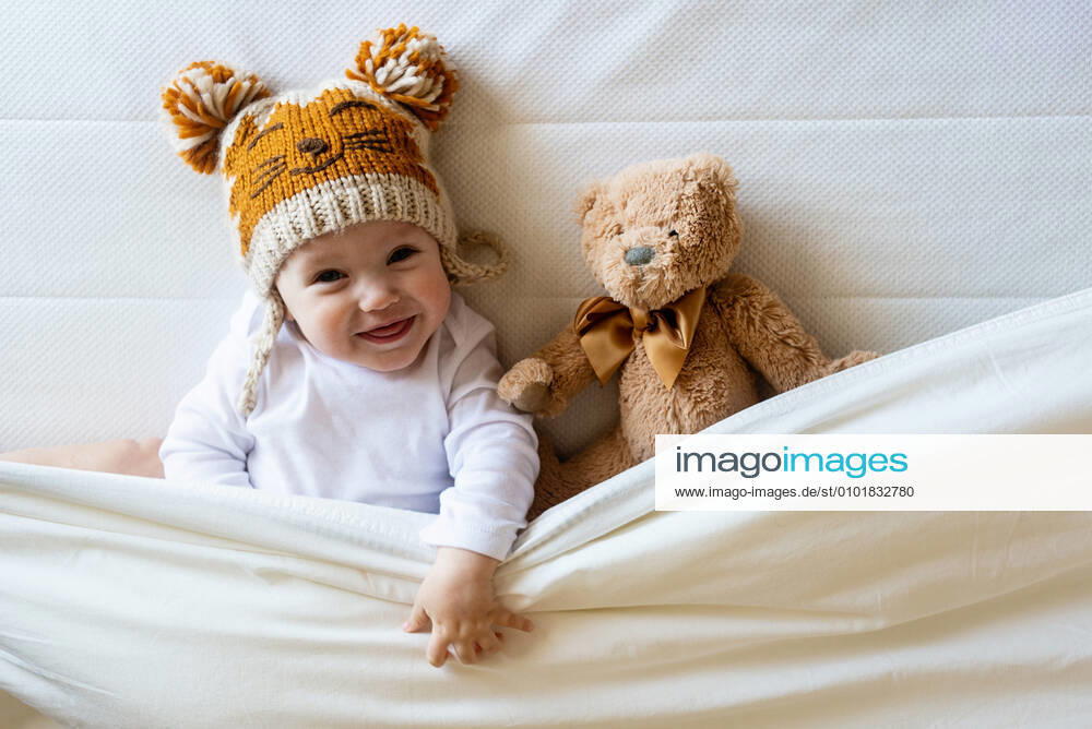 Happy boy with wool cap lying with Teddy bear under the blanket on bed Santa Eulàlia de Ronçana, CT, Spain CR_RAFE200616E-404516-01 ,model released, Symbolfoto