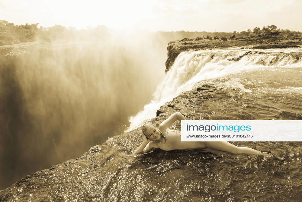 Young girl in the water at the Devils Pool leaning on her elbow, at the edge of the cliff of Victoria Falls. Victoria Falls,Zambia,Young girl in the water at the Devils Pool leaning on her elbow, at the edge of the cliff of Victoria Falls. Young girl in the water at the Devils Pool leaning on her elbow, at the edge of the cliff of Victoria Falls.