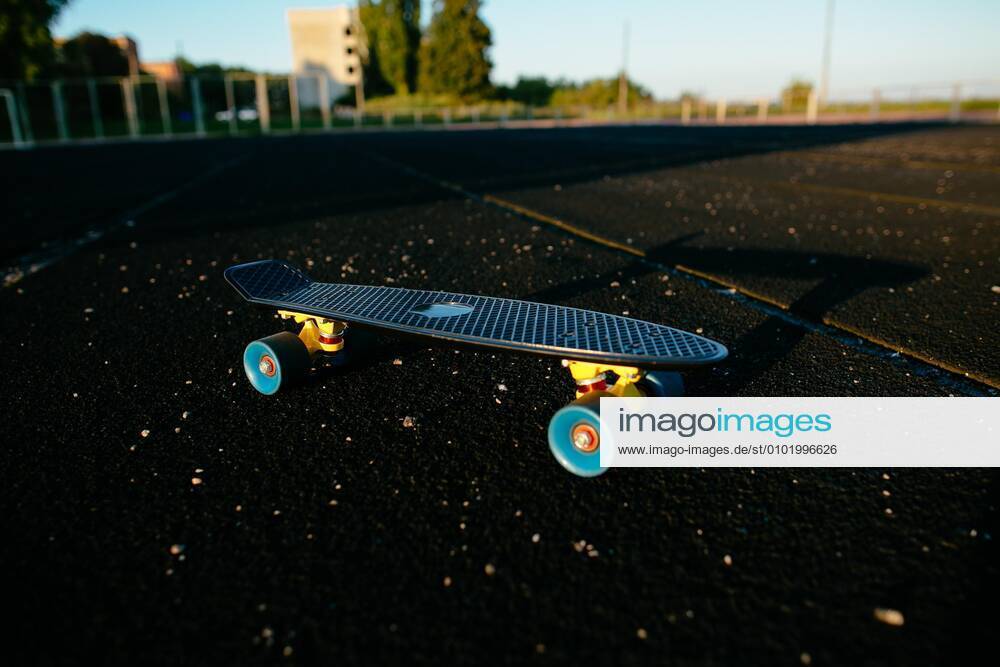 Black penny skateboard on the black sport field.