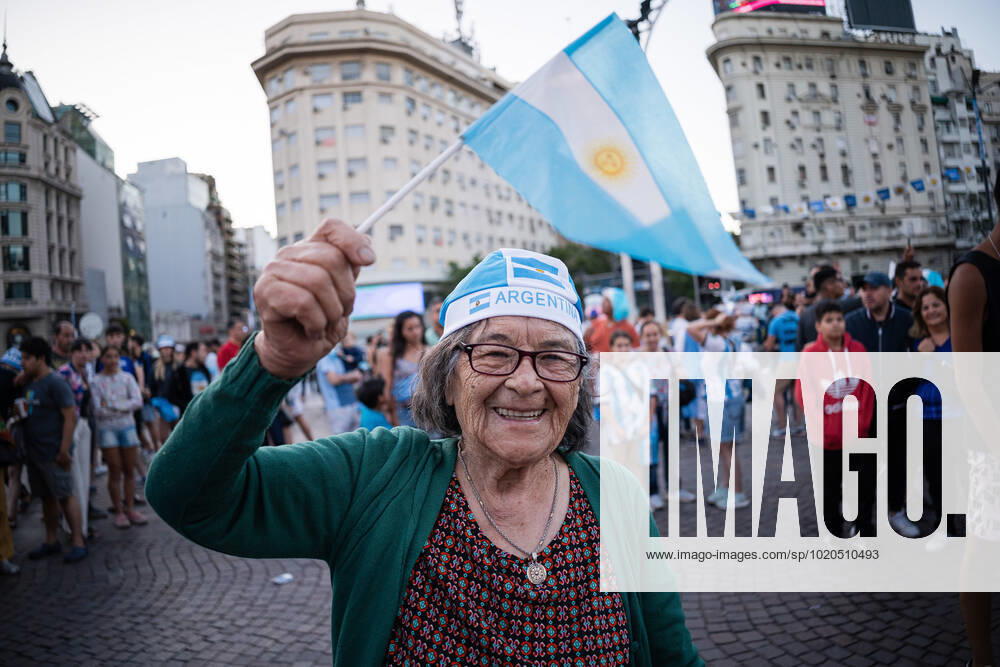 An elderly woman supporting the Argentine national team, Nationalteam waves a flag as she celebrates in the city of Buenos Aires to show support for the team one day before the Qatar 2022 FIFA World Cup, WM, Weltmeisterschaft, Fussball final against the France national football team. Buenos Aires Argentina - ZUMAs197 20221218_zaa_s197_006